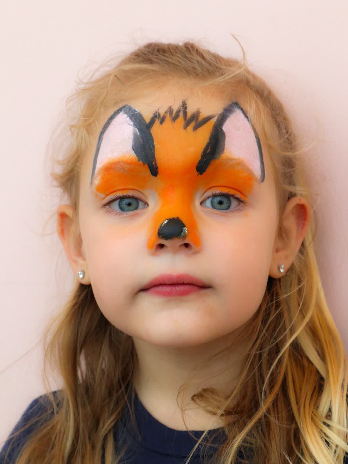 Child with colourful face paint at a party