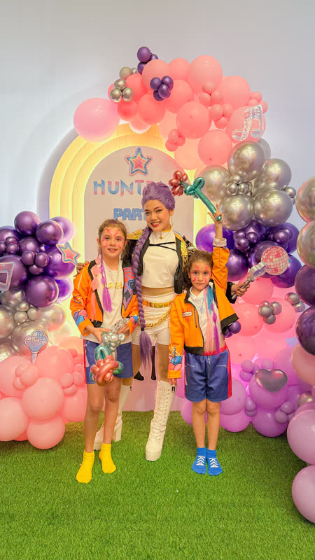 Huntrix Party backdrop with balloons and themed costumes